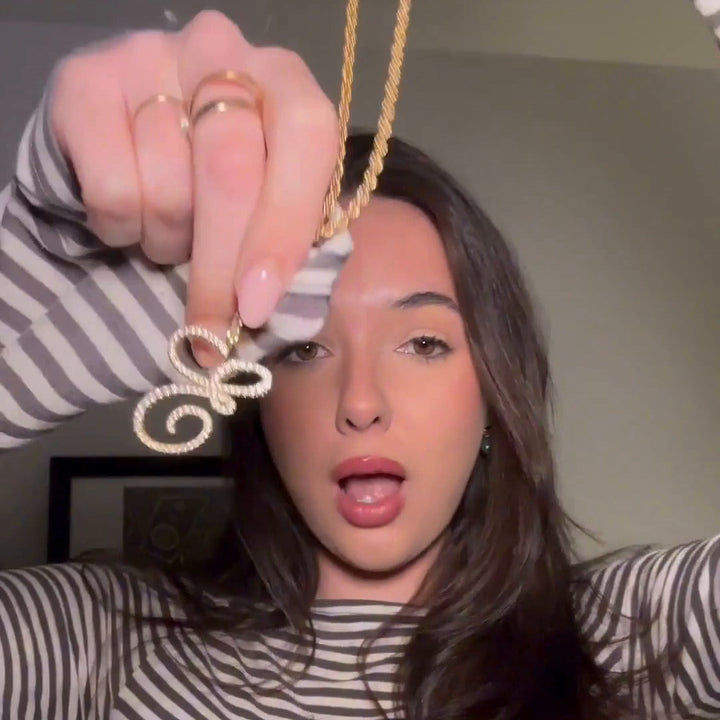 Woman holding a gold necklace with a decorative pendant